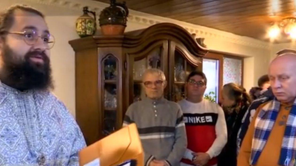 Un preot face Sfânta Liturghie în sufragerie