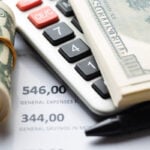 datorie globală, Dolari americani și un calculator, imagine ilustrativă pentru articolul despre taxele vamale impuse de SUA importurilor canadiene