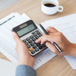Imagine ilustrativă cu o persoană care folosește un calculator