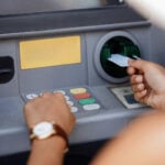 Persoană care folosește un bancomat pentru o operațiune bancară.