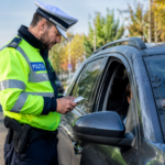 Polițist rutier verifică documentele unui șofer oprit în trafic, lângă o mașină, pe un drum din România – imagine ilustrativă.